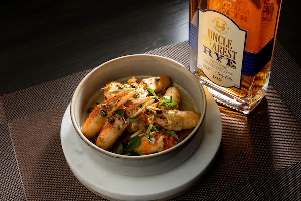 A plated dish beside a bottle of Uncle Nearest Rye